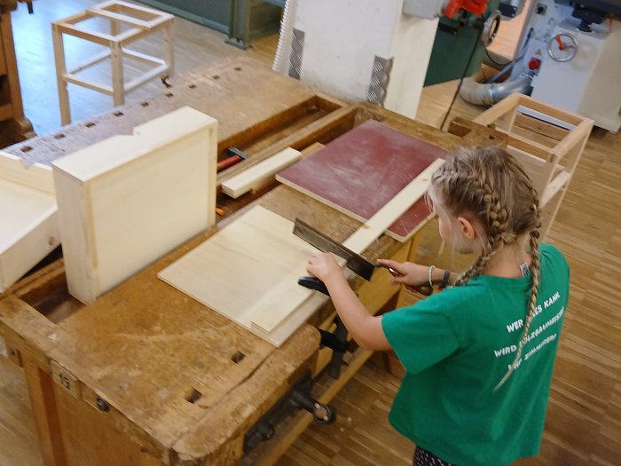 Mit Holz, Wasser & Handwerksfreude: Die KidsAcademy ist in Bruneck angekommen Kind arbeitet an Holztisch und sägt Holz im Werkraum