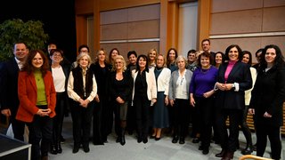 News Gruppenfoto von 22 Personen in einem Innenraum mit Holzwand im Hintergrund