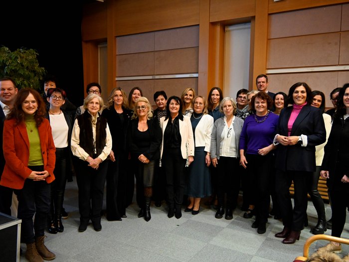 INSIEME nel 2024 Foto di gruppo di 22 persone in un ambiente interno con parete di legno sullo sfondo
