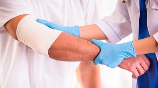 Webinare Arzt untersucht den verbundenen Arm eines Patienten mit blauen Handschuhen