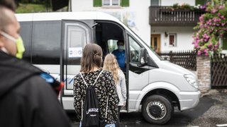 News Menschen mit Masken warten, um in einen weißen Kleinbus einzusteigen