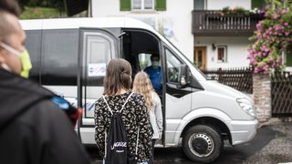 News Menschen mit Masken warten, um in einen weißen Kleinbus einzusteigen