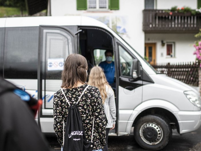 „Der Schulbus wird nicht ausfallen!“ Menschen mit Masken warten, um in einen weißen Kleinbus einzusteigen