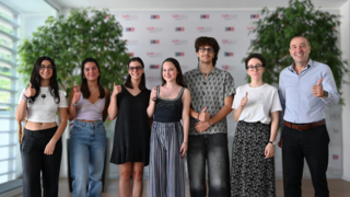 News Gruppe junger Menschen und ein Mann zeigen Daumen hoch und lächeln im Innenraum