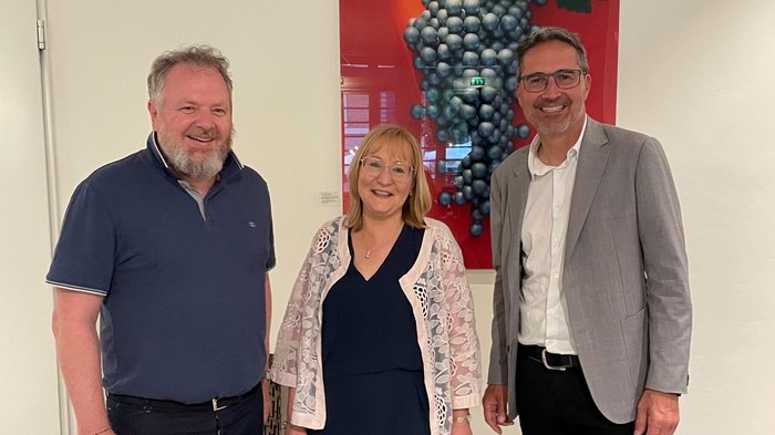 Gert Lanz, Petra Holzer und Arno Kompatscher © lvh.apa Drei lächelnde Personen vor einem Bild von Trauben an einer Wand
