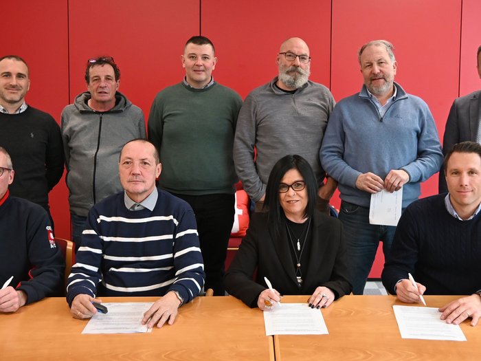 Variables Lohnelement auch für 2025 bestätigt Zehn Personen bei Vertragsunterzeichnung vor roter Wand