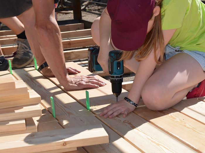 © lvh.apa Mann und Frau arbeiten gemeinsam an Holzprojekten mit Bohrmaschine im Freien