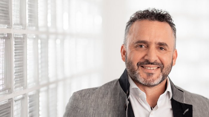 Bauhandwerk: variables territoriales Lohnelement verdoppelt Lächelnder Mann vor einer Wand mit Glasbausteinen