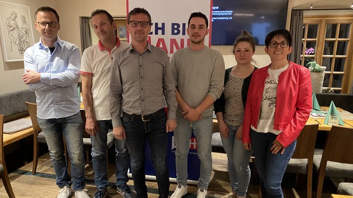 Stabübergabe im Handwerk in Klausen Sechs Personen stehen in einem Raum mit Tischen und Stühlen