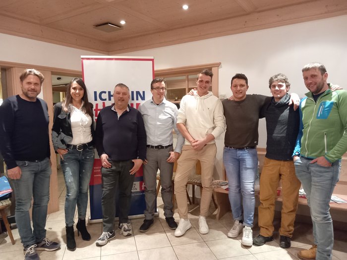 lvh Lüsen: Kier bleibt Obmann Gruppe von acht Personen steht vor einem Werbebanner in einem Raum