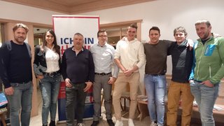 News Gruppe von acht Personen steht vor einem Werbebanner in einem Raum