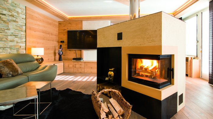 Holzofen: eine gute und sichere Alternative Gemütliches Wohnzimmer mit Kamin, Ledersofa und TV an Holzvertäfelung