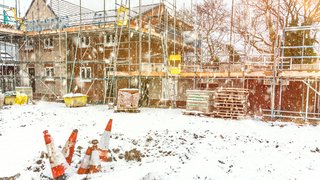 Webinare Baustelle eines Hauses im Winter mit Schnee und Verkehrskegeln