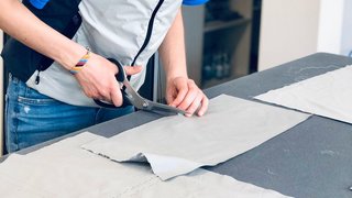 News Frau schneidet Stoff mit Schere auf einem Tisch