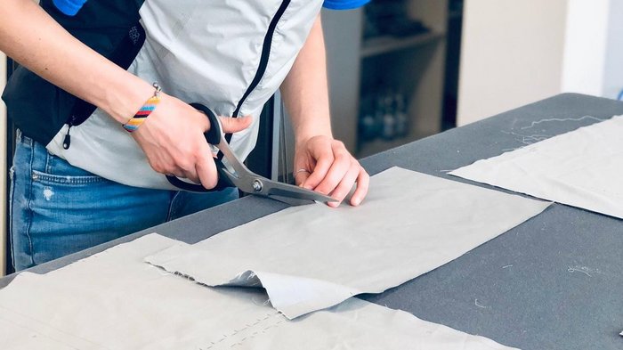 Nähkünste der Tapezierer gerade jetzt unverzichtbar Frau schneidet Stoff mit Schere auf einem Tisch