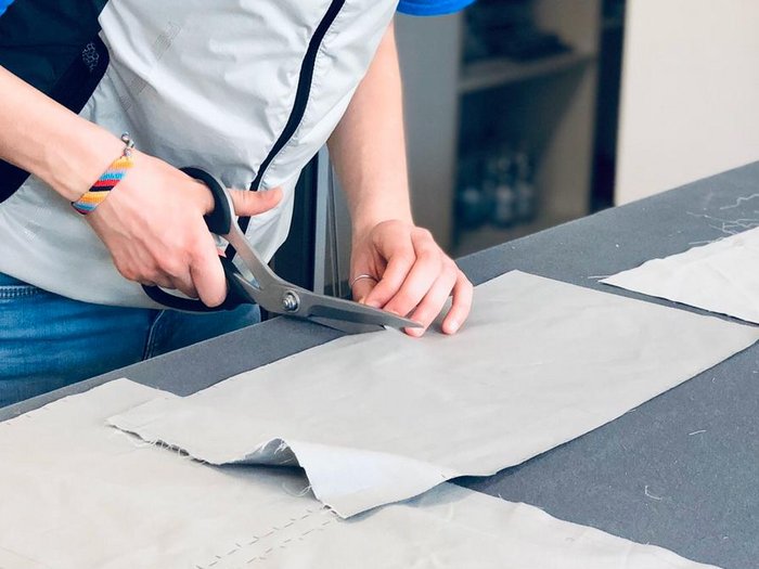 Nähkünste der Tapezierer gerade jetzt unverzichtbar Frau schneidet Stoff mit Schere auf einem Tisch