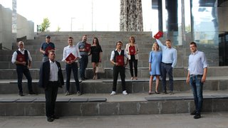 News Gruppe von elf Menschen auf Treppen mit roten Urkunden in der Hand