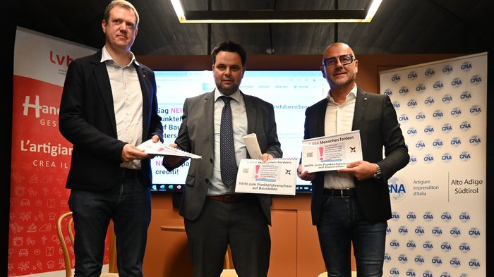 Patente a crediti: consegna delle firme Tre uomini tengono firme contro la patente a punti nei cantieri