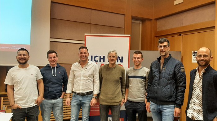 Führungswechsel Sieben Männer stehen nebeneinander in einem Konferenzraum vor einem Banner