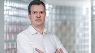 News Uomo con camicia bianca con le braccia incrociate davanti a sfondo chiaro