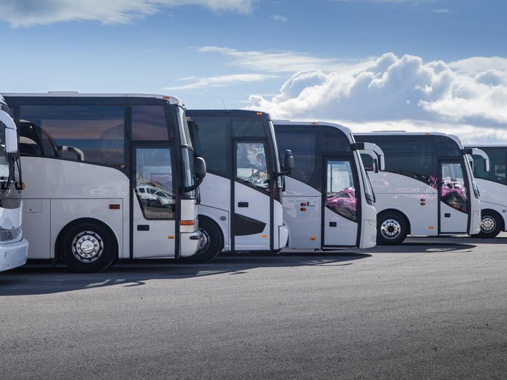 Mietwagen- und Taxiunternehmer Reihe geparkter weißer Reisebusse unter blauem Himmel