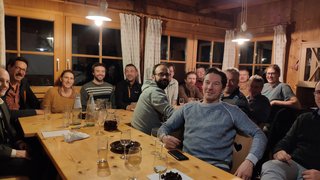 News Gruppe von Menschen sitzt abends in einem gemütlichen Raum um einen Holztisch