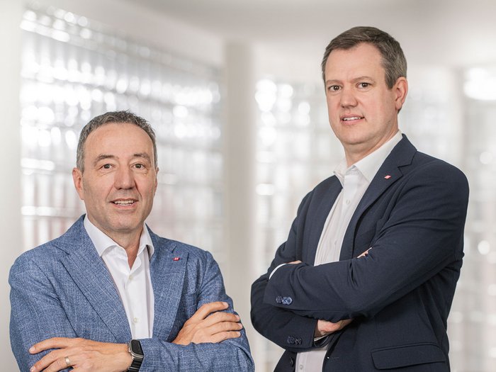 Neue Förderung für Sicherheitsanlagen in Südtirol Zwei Männer in Anzügen mit verschränkten Armen vor hellem Hintergrund