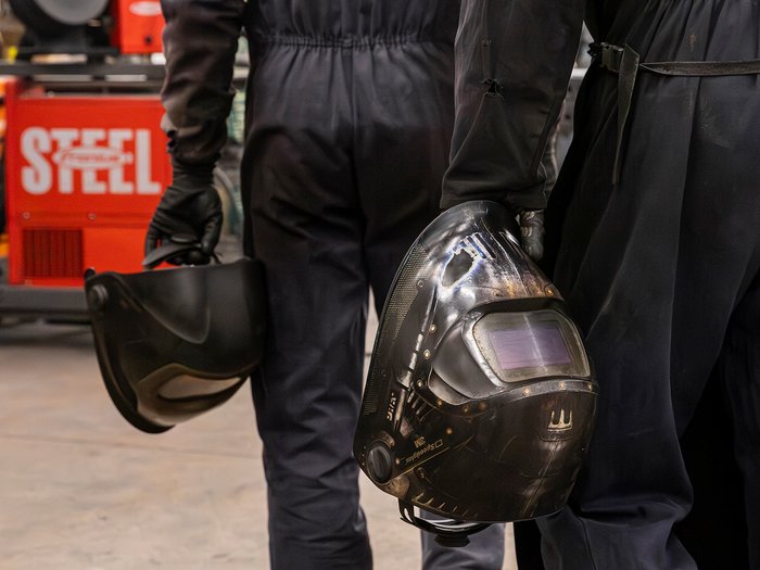 La sicurezza è un lavoro fatto a mano Due saldatori tengono i loro caschi da saldatura in una officina