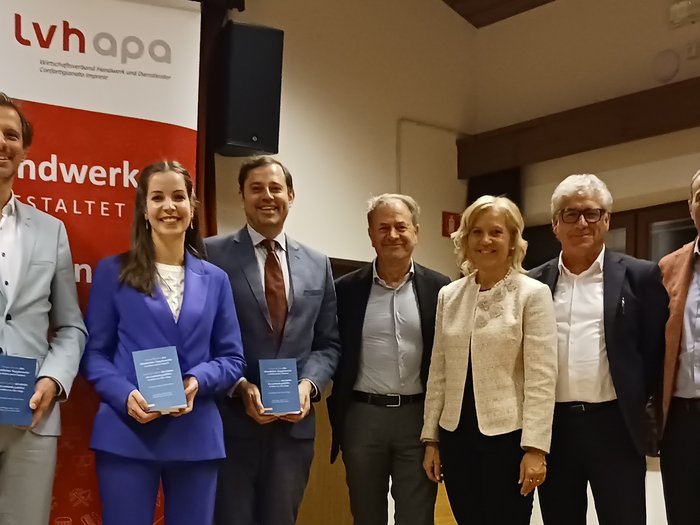 Einblick in den neuen Vergabekodex: Erfolgreicher Infoabend Sieben Personen in Anzügen posieren vor einem LVH-Banner mit Büchern in der Hand