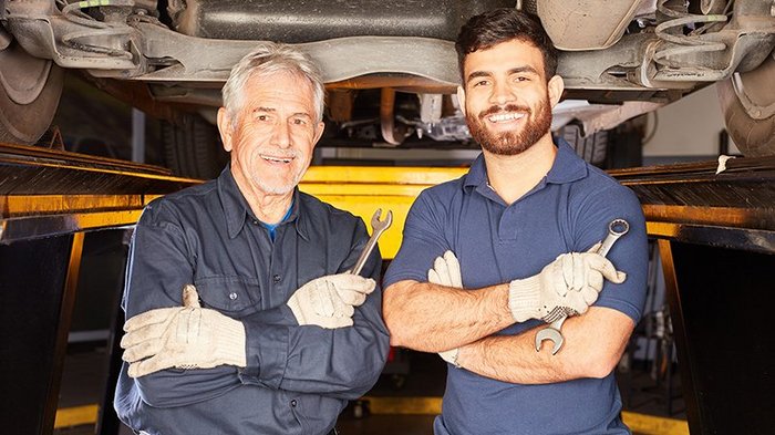 Meisterkurse: lvh erfreut über Kooperationsvertrag mit Handelskammer Zwei automechaniker mit schraubenschlüsseln unter einem angehobenen auto