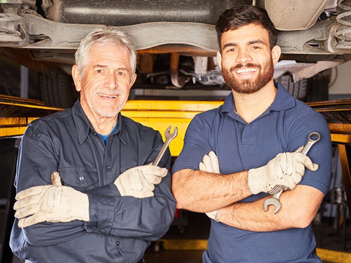 Meisterkurse: lvh erfreut über Kooperationsvertrag mit Handelskammer Zwei automechaniker mit schraubenschlüsseln unter einem angehobenen auto