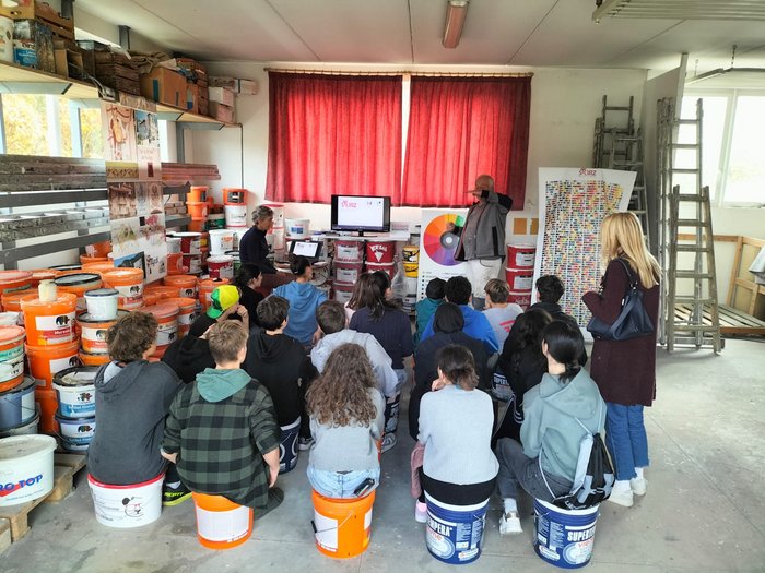 In giro per la Bassa Atesina per promuovere le professioni pratiche Bambini seduti su secchi in un laboratorio di vernici ascoltano una lezione