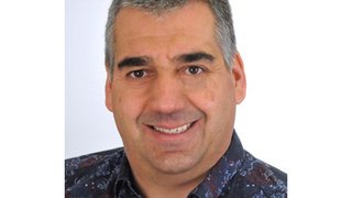 News Porträt eines lächelnden Mannes mit kurzen grauen Haaren und gemustertem Hemd