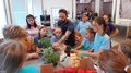 Kids-Academy 2024: Das große Finale Kinder und Mann lernen in einer Küche mit frischen Paprikaschoten und Kräutern