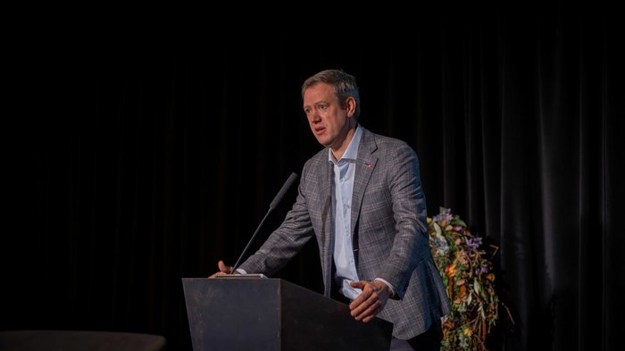 Crescita in equilibrio Uomo che parla al podio con sfondo di tende nere