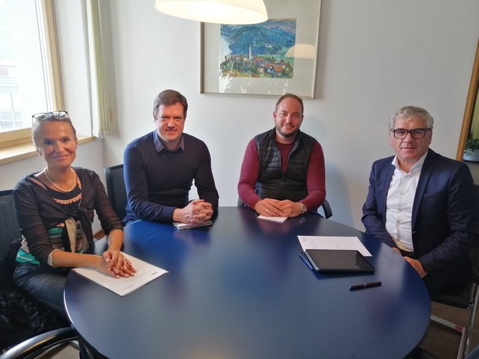 La collaborazione è fondamentale in tempi di crisi Quattro persone in riunione attorno a un tavolo blu in un ufficio