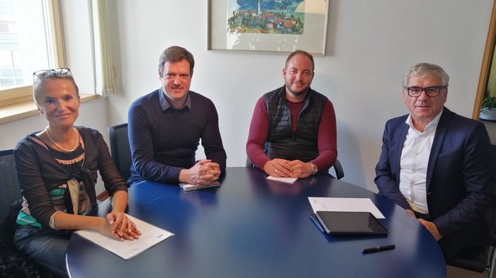 La collaborazione è fondamentale in tempi di crisi Quattro persone in riunione attorno a un tavolo blu in un ufficio