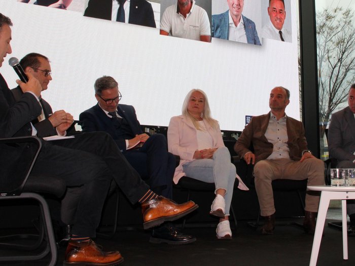 Focus sulle sfide e le prospettive future del trasporto merci transalpino Discussione sul palco con sei persone sedute davanti a uno schermo grande con ritratti