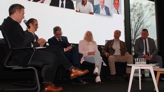 News Discussione sul palco con sei persone sedute davanti a uno schermo grande con ritratti