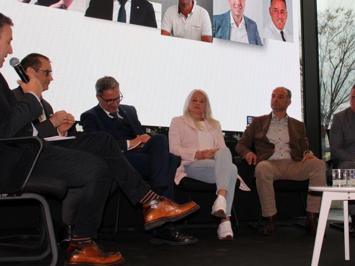 Herausforderungen und Zukunftsperspektiven im alpenquerenden Güterverkehr im Fokus Podiumsdiskussion mit sechs Teilnehmern vor großem Bildschirm mit Porträts