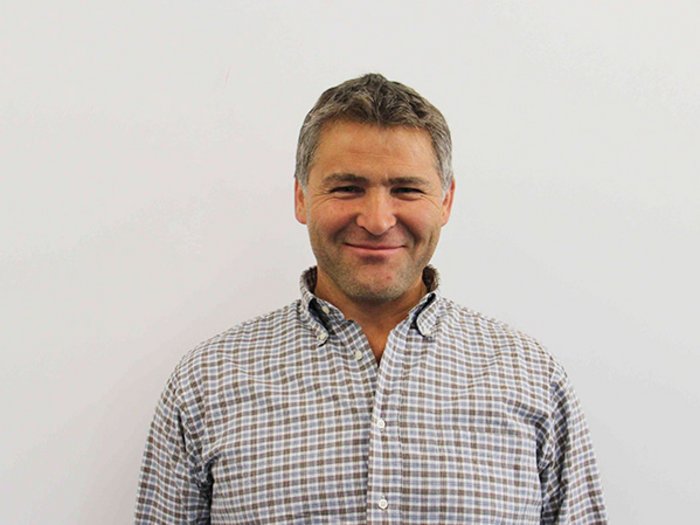 Öffentliche Aufträge sollen primär an lokale Firmen gehen Mann mittleren Alters mit kariertem Hemd lächelt vor weißer Wand