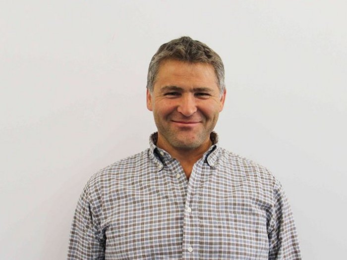 Öffentliche Aufträge sollen primär an lokale Firmen gehen Mann mittleren Alters mit kariertem Hemd lächelt vor weißer Wand