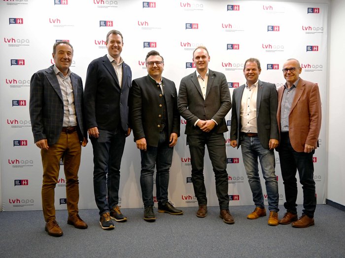 Der lvh im Dialog mit der Freien Fraktion Sechs Männer stehen vor einer Wand mit LVH-Logos für ein Gruppenfoto