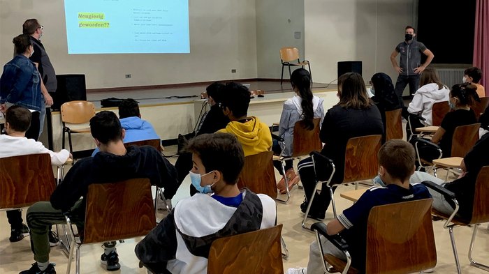 Traumberufe im Handwerk und in der Gastronomie Schüler sitzen mit Masken und schauen eine Präsentation in einem Klassenraum an