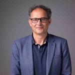 Das lvh-Team Porträt eines lächelnden Mannes mit Brille und blauem Sakko vor grauem Hintergrund