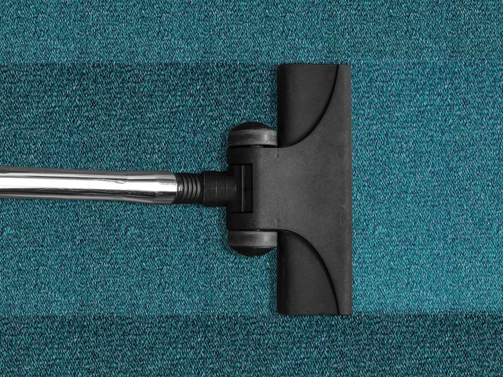 Reinigungsunternehmer Staubsaugeraufsatz auf blauem Teppichboden