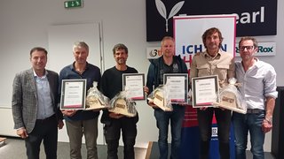 News Sechs Männer bei einer Auszeichnung mit Urkunden und Geschenken in Innenraum