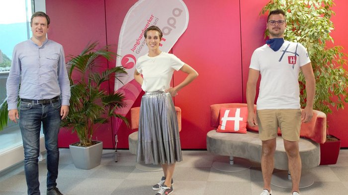 Junghandwerker wählen neuen Landesausschuss Drei Menschen stehen vor roter Wand mit Pflanzen und Sitzgelegenheiten