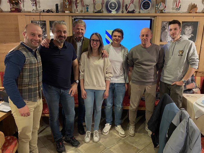 Rafforzare l’artigianato: impulsi da Gais Sette persone in piedi davanti a uno schermo con stemma in una stanza con trofei