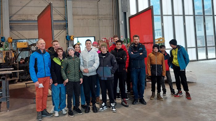 Giovani artigiani di lvh.apa e Giovani Albergatori (HGJ) ospiti della Scuola media di Vandoies Gruppo di giovani e due adulti in un capannone industriale